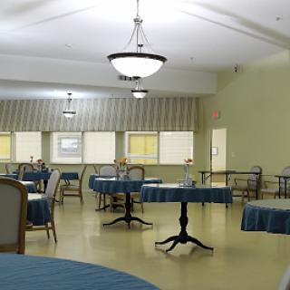 A spacious and lightly furnished dining area, featuring tables and chairs beneath soft lighting.