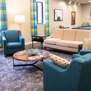A cozy living room with blue chairs and a beige sofa arranged around a wooden coffee table.