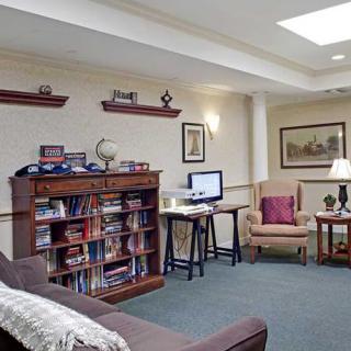A cozy living room with a computer desk, bookshelf, and comfortable seating.
