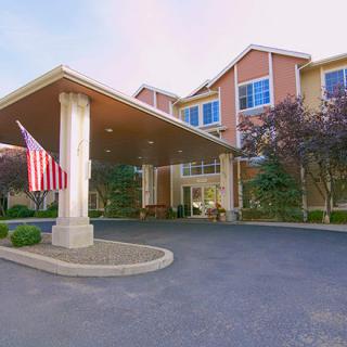 Exterior view of a building entrance with an American flag and surrounding trees.