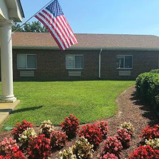 A vibrant front yard featuring an American flag and colorful flowerbeds.