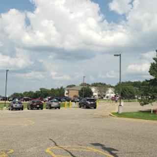 A view of a parking lot with several cars under a partly cloudy sky.