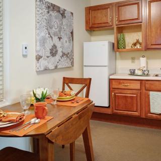 A cozy kitchen and dining area with wooden cabinets and a neatly set table.