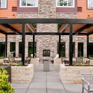 A modern outdoor patio featuring a central fireplace and comfortable seating surrounded by sleek architecture.