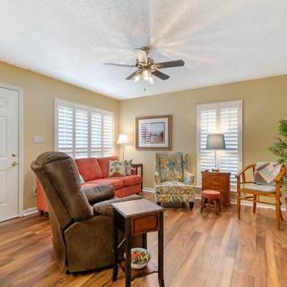 A cozy living room with stylish furniture, wood flooring, and a ceiling fan.