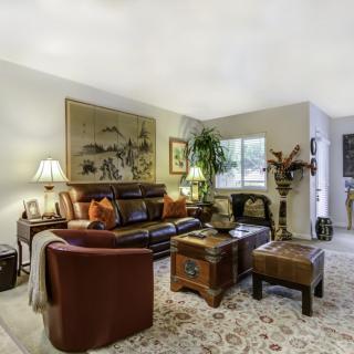 A cozy and elegantly decorated living room with a leather sofa, wooden furniture, and warm lighting.