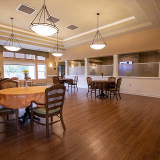 A spacious dining room with wooden floors and elegant lighting.