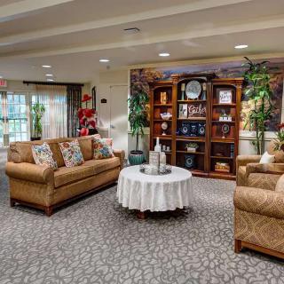 A cozy living room with sofas, a round table, and a bookshelf adorned with decor items.