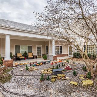 A well-maintained courtyard garden with a pathway, outdoor seating, and landscaping in front of a building.