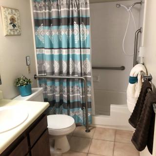 A well-organized bathroom with a shower, toilet, and sink, featuring a striped shower curtain and towels.