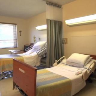 A hospital room with two adjustable patient beds separated by a curtain.