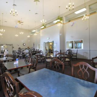An empty dining room with neatly arranged tables and chairs under bright lighting.