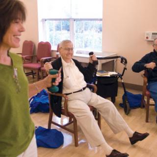 A group exercise session for seniors, focusing on strength training with dumbbells.