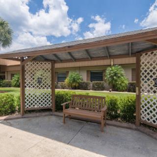A sunny outdoor area featuring a wooden bench and decorative lattice, ideal for relaxation.