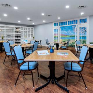 A cozy library reading room with tables and chairs surrounded by bookshelves.