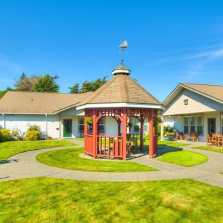 A charming gazebo surrounded by a well-maintained garden with clear blue skies overhead.