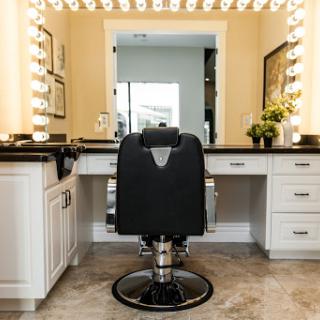 A stylish beauty vanity setup complete with bright lighting and a comfortable black chair.