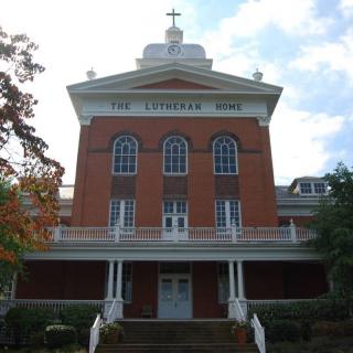 A historic brick church building with a prominent front facade and a cross on top.