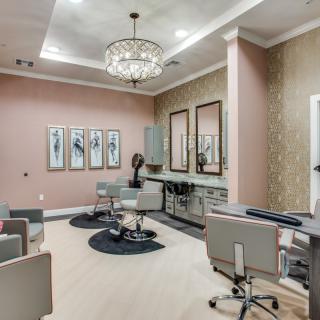 A modern and elegant salon interior with plush seating, chandeliers, and stylish artwork.