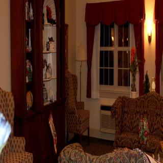 A cozy living room with sofas, an armchair, a bookshelf, and a window with curtains.