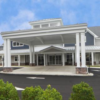 A modern building entrance with a large canopy and landscaped surroundings.