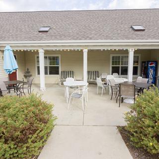 A cozy outdoor patio with tables and chairs under a porch.