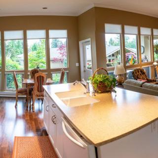 Spacious open-concept kitchen and living area with large windows and wooden flooring.