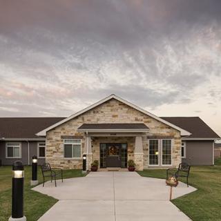 A building with a stone facade and a welcoming entrance under a cloudy sky.