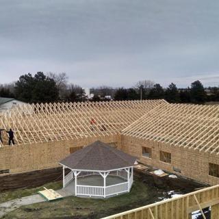 A construction site with wooden roofing framework in progress and a gazebo located in the center.