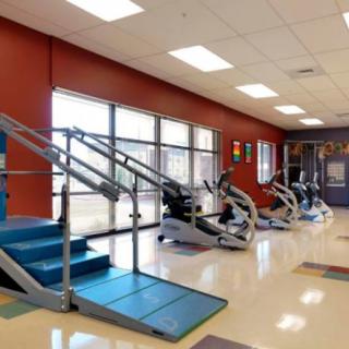 A gym setup in a medical facility, featuring various exercise machines and ramps for rehabilitation.