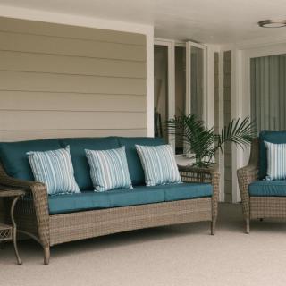 Outdoor patio area with wicker furniture and blue cushions.
