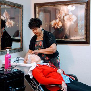 A hairstylist washing an elderly woman's hair in a salon.
