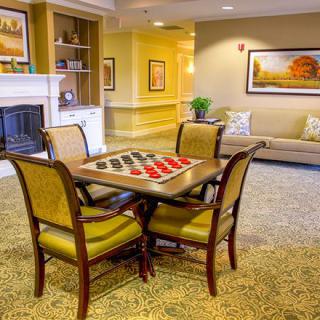A cozy lounge area featuring a checkers board, comfortable seating, and a fireplace.