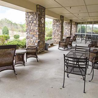 A covered patio with tables and chairs, offering a garden view.