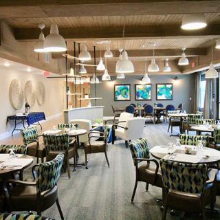 A modern restaurant dining area with elegant tables and chairs, decorated with artistic lighting and wall art.