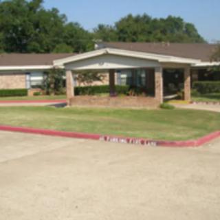 A suburban brick house with a driveway and well-maintained lawn.