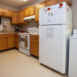 A spacious kitchen featuring wooden cabinets, a white refrigerator, and a stove.