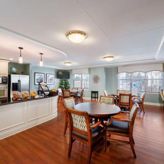 A bright and spacious dining area connected to a modern kitchen with hardwood floors and elegant lighting.