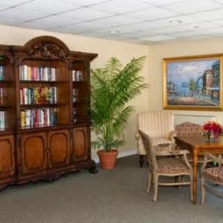A cozy room with a wooden bookshelf, a potted plant, and a small table surrounded by chairs.