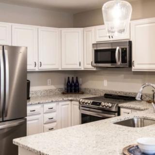 A modern kitchen with white cabinets and stainless steel appliances.