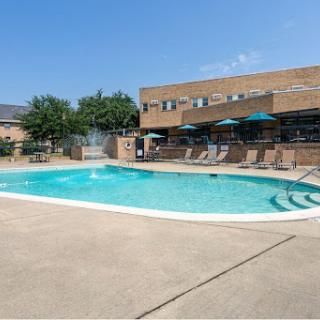 A serene outdoor swimming pool surrounded by seating and greenery, perfect for relaxation on a sunny day.