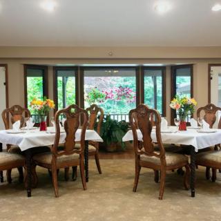 An elegant dining room with beautifully set tables and floral decorations by large windows.