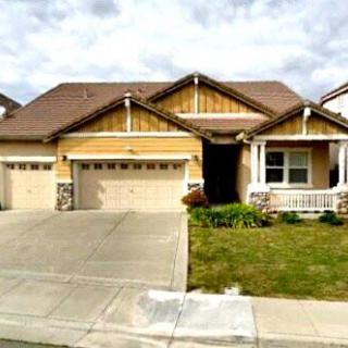 A suburban house with a three-car garage and a well-maintained lawn.