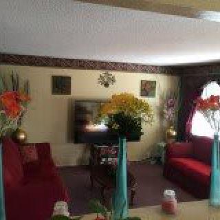 A cozy living room with red sofas, floral decorations, and a television.
