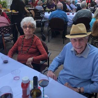 An elderly couple enjoying an outdoor meal at a restaurant.