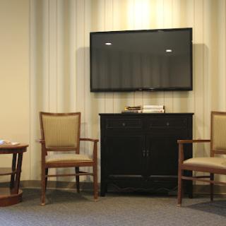 A waiting room featuring a television, a small table, and two chairs.