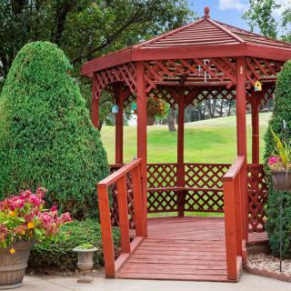 A charming wooden gazebo nestled in a beautifully maintained garden with lush greenery.