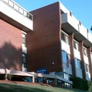 A modern brick building with large windows and balconies on a clear day.