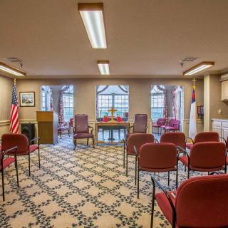 A small room set up for a ceremony with chairs, flags, and large windows.