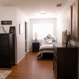A minimalist bedroom with hardwood flooring and modern furniture.